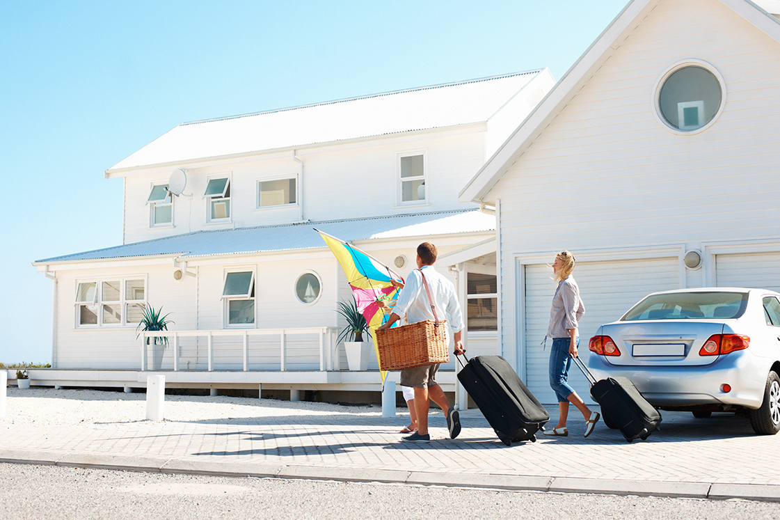 Couple carrying luggage into a vacation home